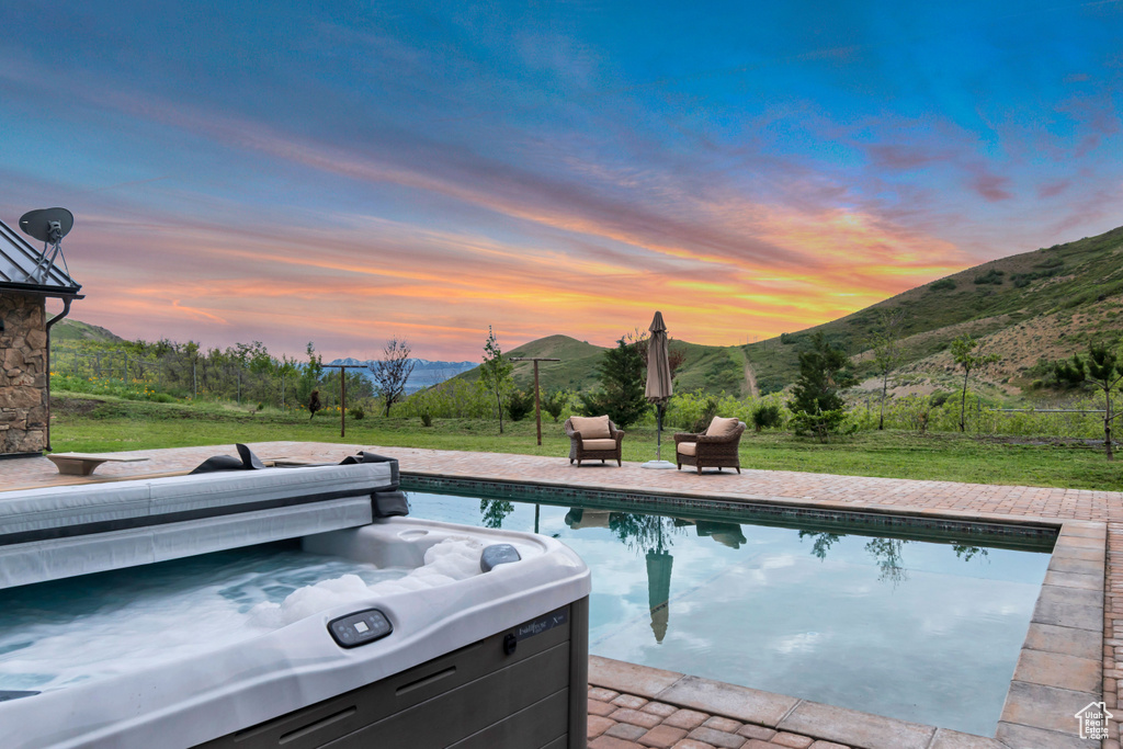 Swimming pool featuring a hot tub, a mountain view, a yard, and a patio area
