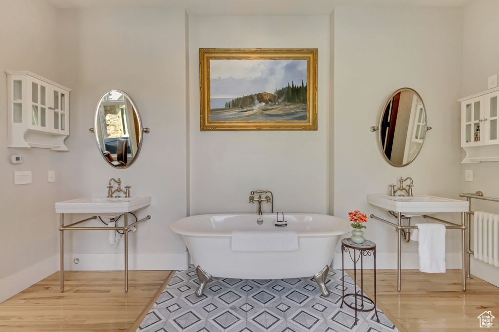 Bathroom featuring wood finished floors, radiator heating unit, a freestanding tub, and baseboards