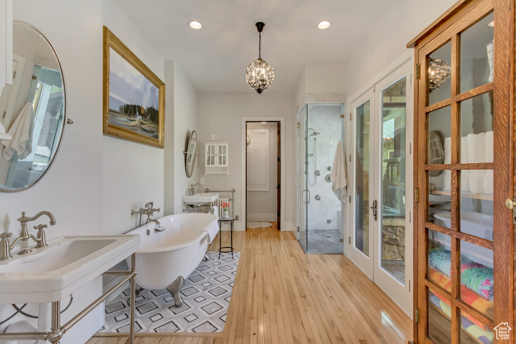 Full bath with a stall shower, a soaking tub, wood finished floors, a chandelier, and recessed lighting