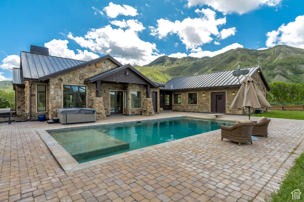 Swimming pool with a hot tub, a mountain view, a patio area, and a diving board