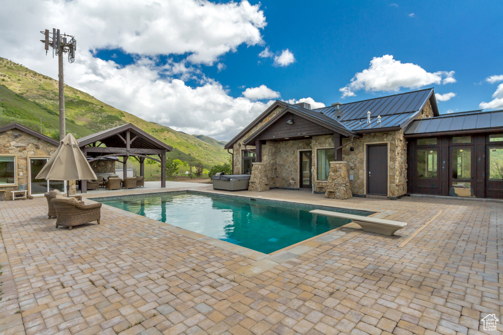 Outdoor pool with a gazebo, outdoor lounge area, a mountain view, a patio area, and a hot tub