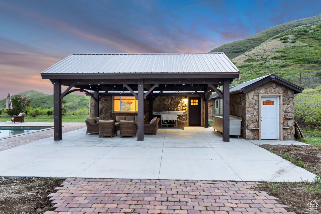 Patio terrace at dusk featuring a gazebo, an outdoor hangout area, and an outdoor pool