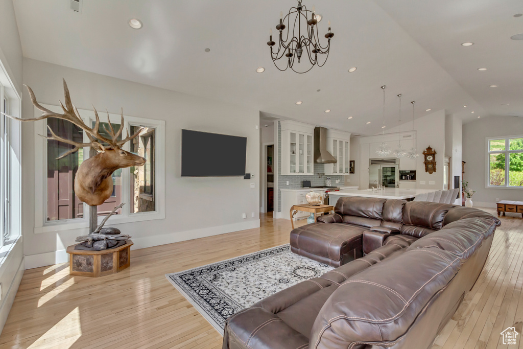 Living room with light wood-style flooring, lofted ceiling, a chandelier, baseboards, and recessed lighting