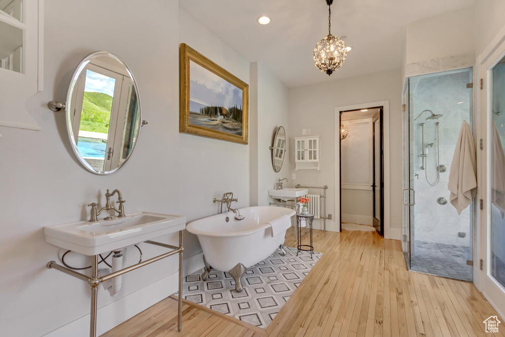 Bathroom with a stall shower, hardwood / wood-style flooring, a soaking tub, a chandelier, and recessed lighting