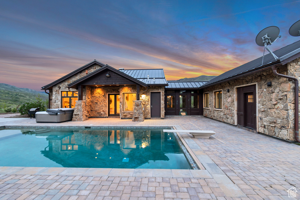 Swimming pool with a hot tub, a patio area, and a diving board