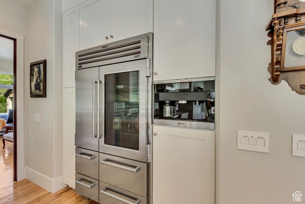 Bar area with stainless steel built in refrigerator, light wood-type flooring, and baseboards