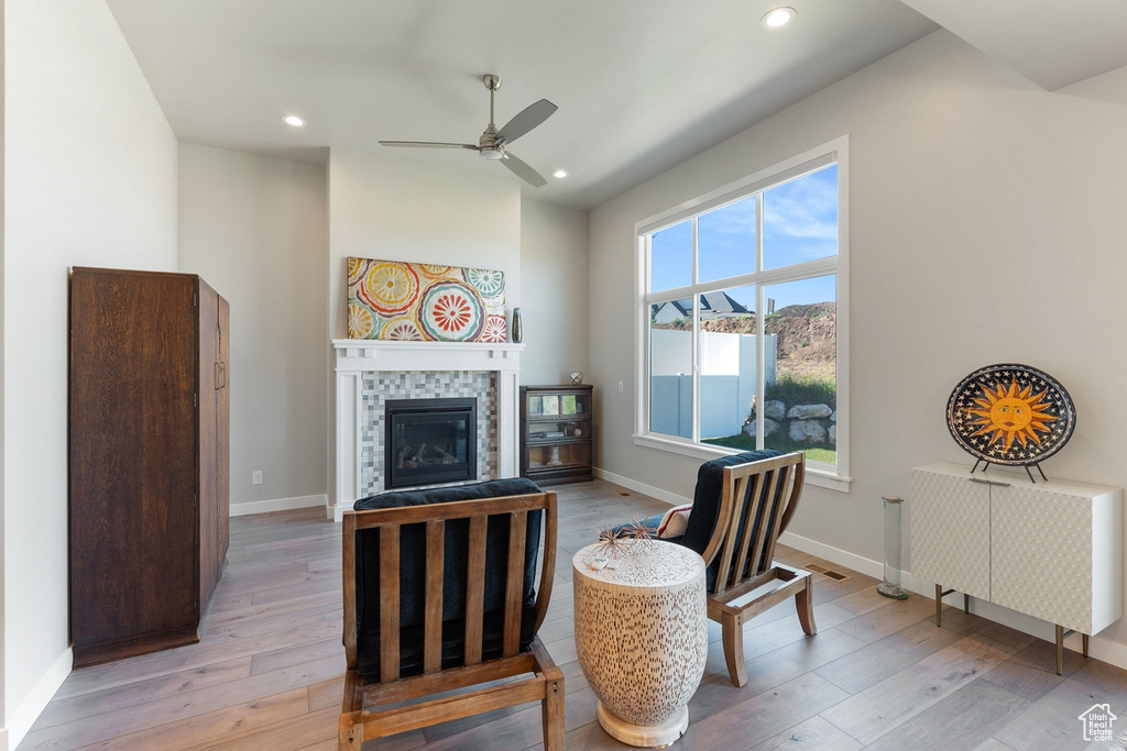 Living area with light wood finished floors, a ceiling fan, a fireplace, recessed lighting, and baseboards