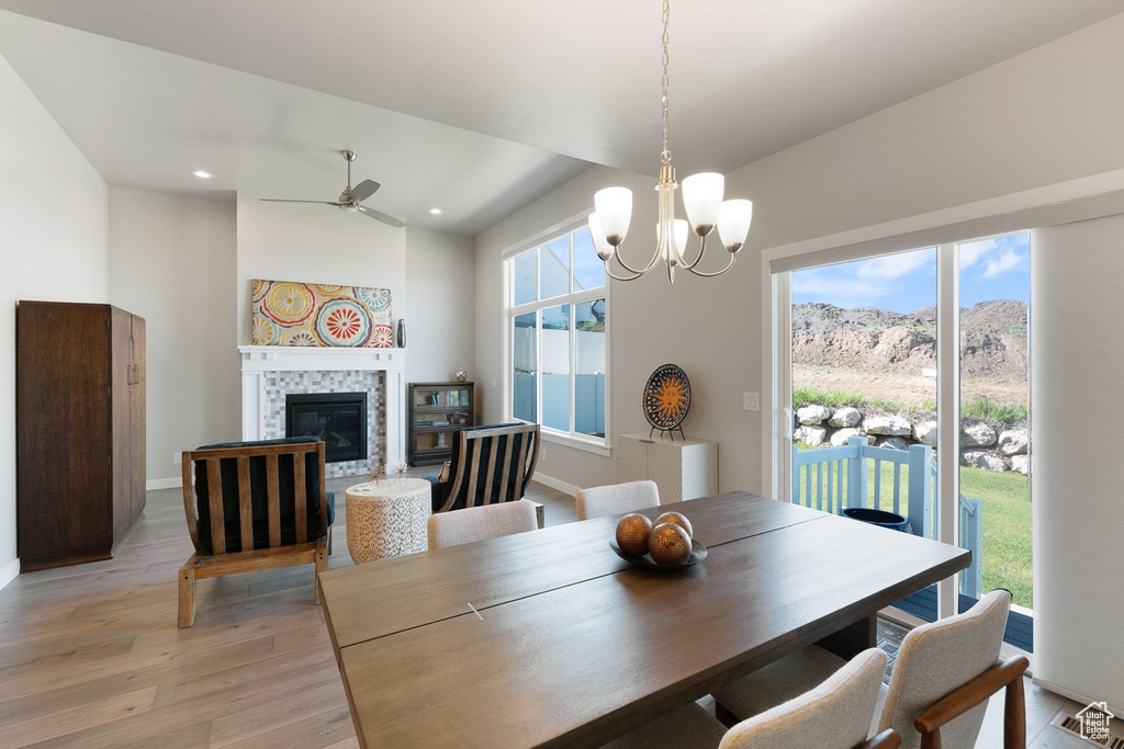 Dining space featuring light wood-style flooring, a tile fireplace, ceiling fan, a chandelier, and recessed lighting