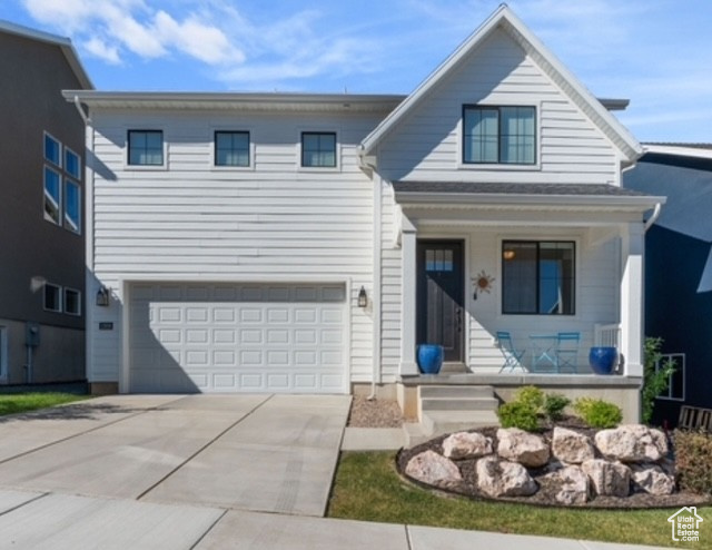 View of front of home with covered porch, driveway, and an attached garage