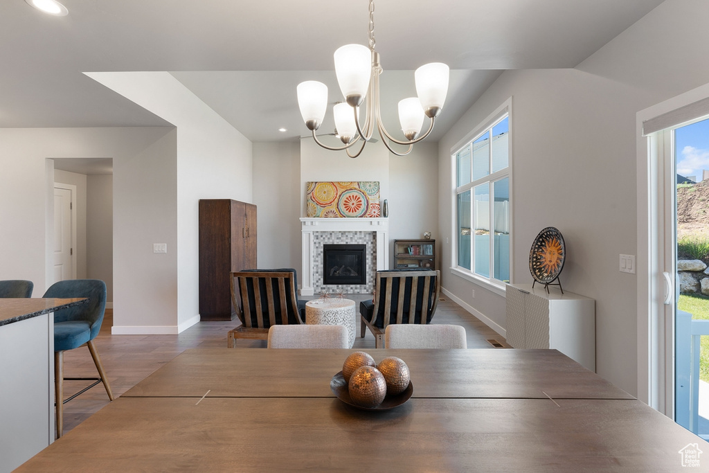 Dining space with baseboards, wood finished floors, a chandelier, recessed lighting, and a fireplace