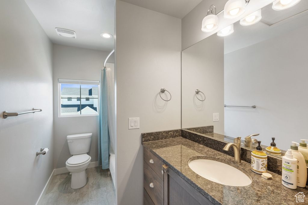 Full bath featuring vanity, toilet, baseboards, and shower / bath combo