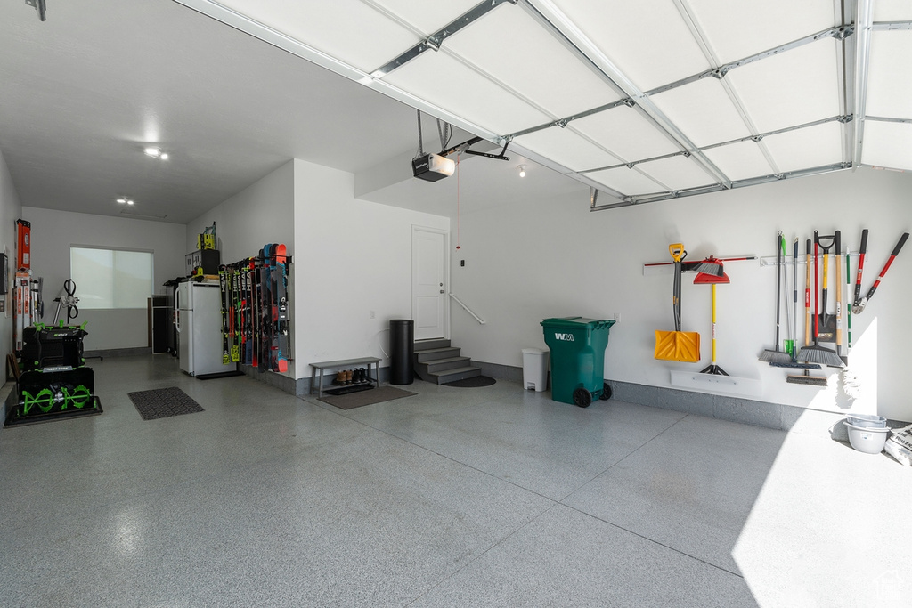 Garage featuring a garage door opener, freestanding refrigerator, and baseboards