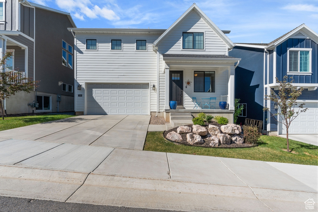 View of front facade featuring covered porch, a garage, and driveway