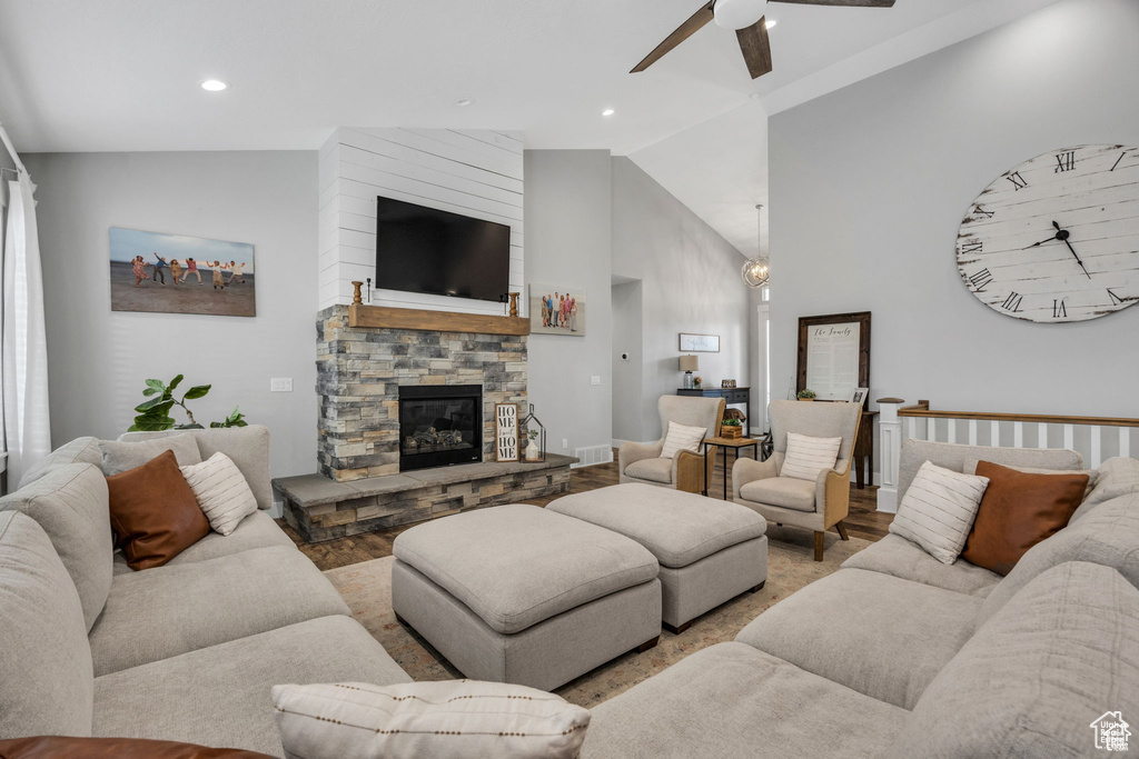 Living room with ceiling fan, a stone fireplace, wood finished floors, high vaulted ceiling, and recessed lighting