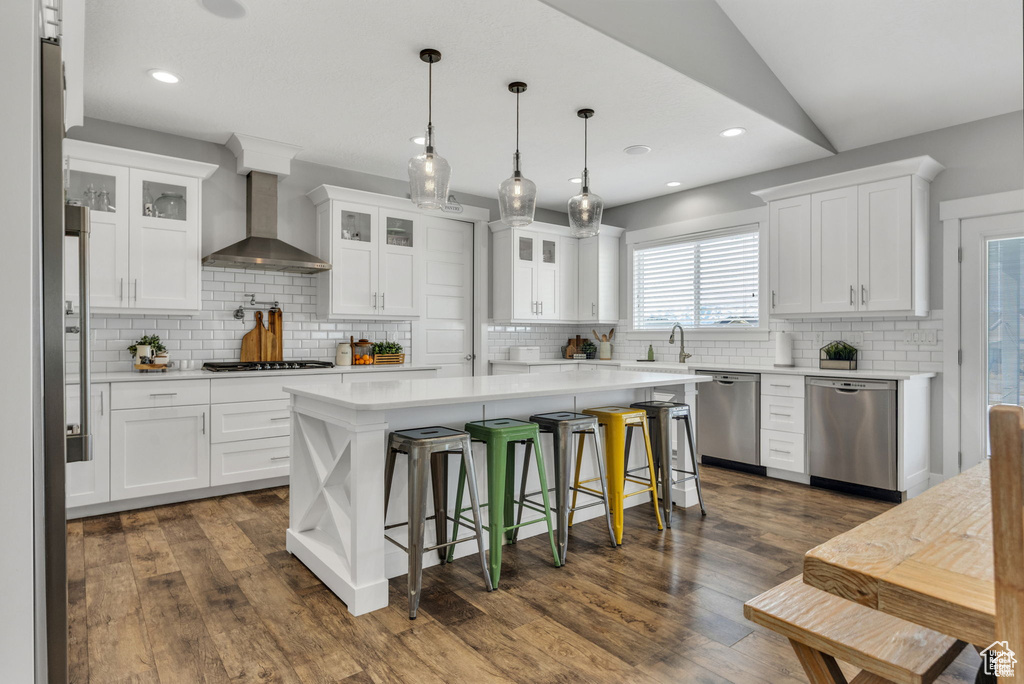 Kitchen with stainless steel dishwasher, wall chimney exhaust hood, backsplash, and recessed lighting
