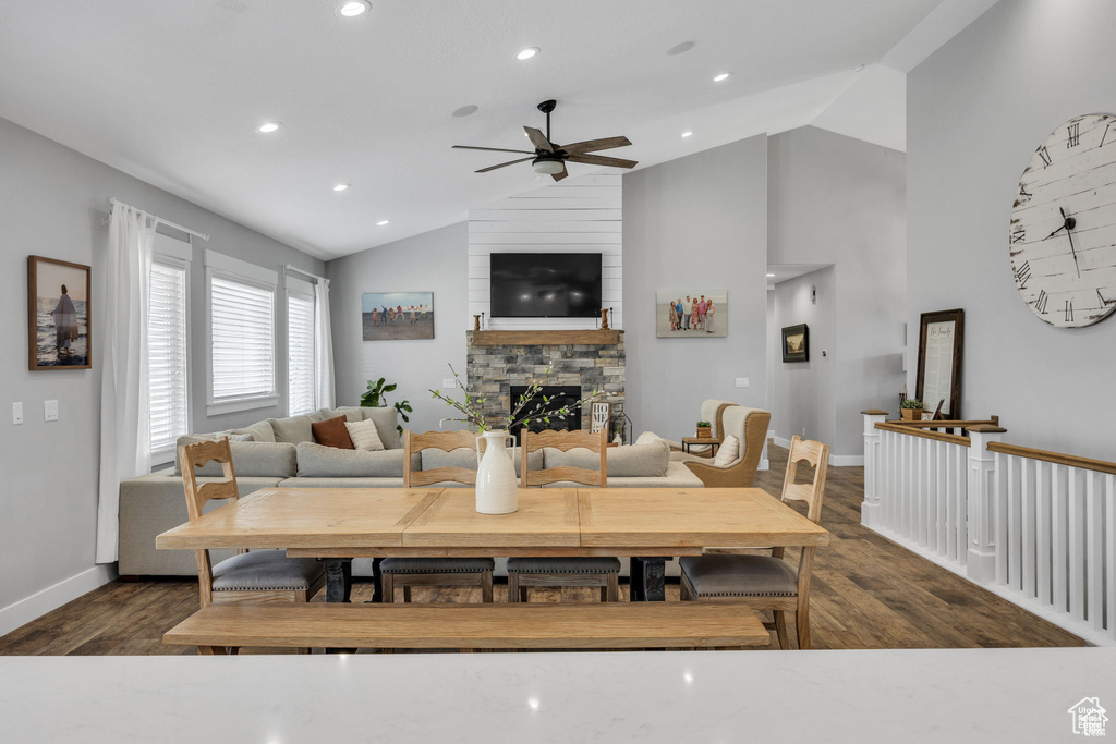 Dining room with lofted ceiling, ceiling fan, wood finished floors, a stone fireplace, and recessed lighting