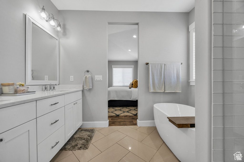Full bathroom featuring vanity, a soaking tub, and tile patterned floors