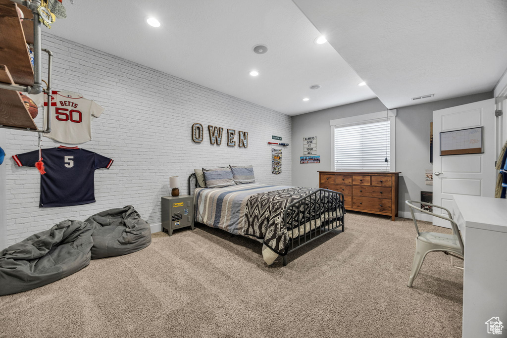 Bedroom featuring light carpet, brick wall, and recessed lighting