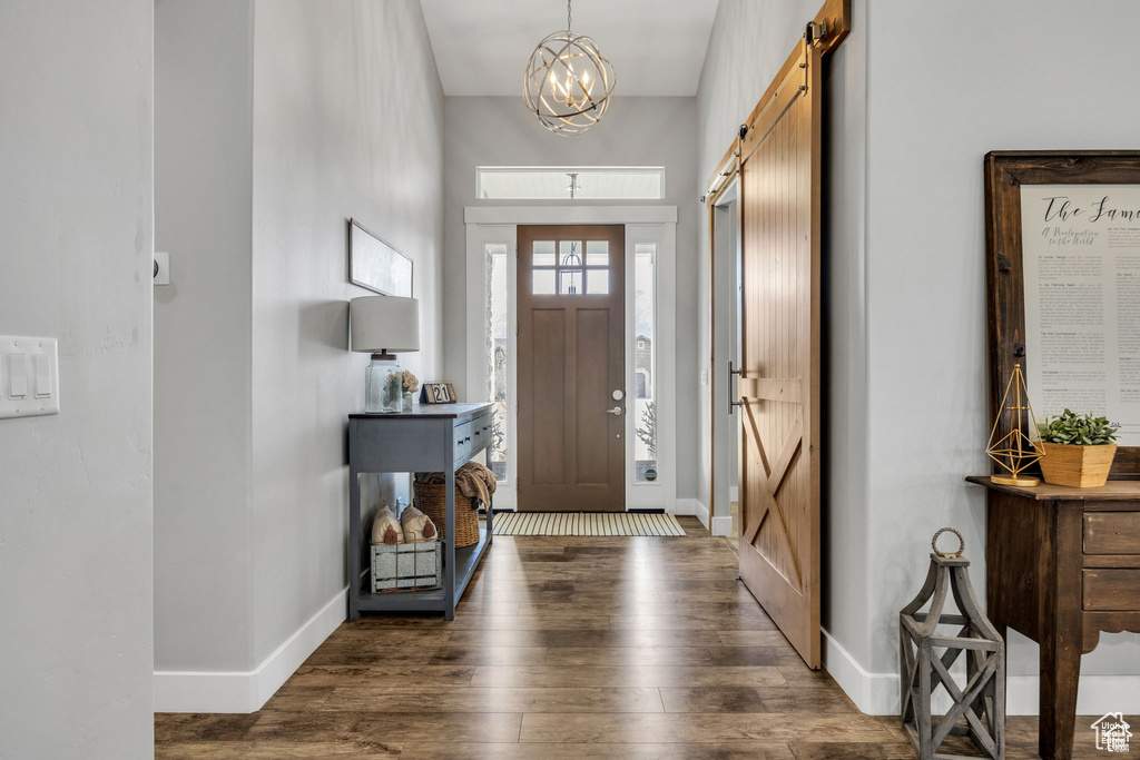 Entryway with a barn door, wood finished floors, and a chandelier
