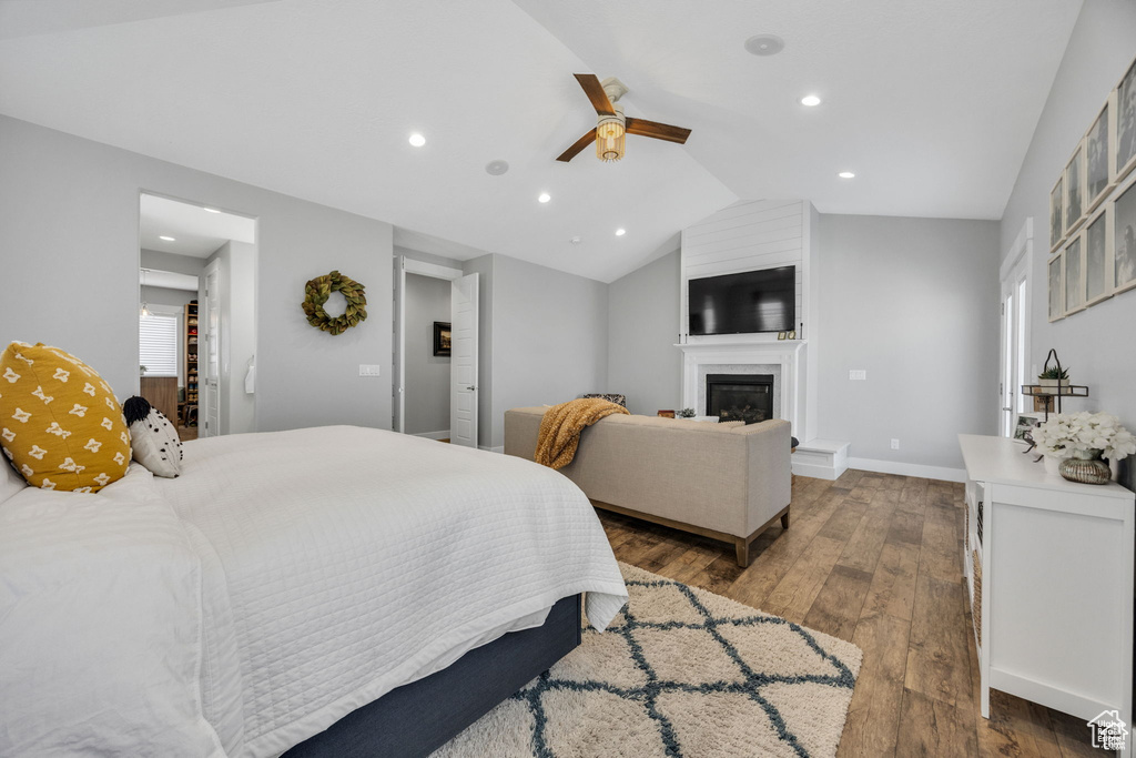 Bedroom with hardwood / wood-style floors, recessed lighting, lofted ceiling, a glass covered fireplace, and a ceiling fan
