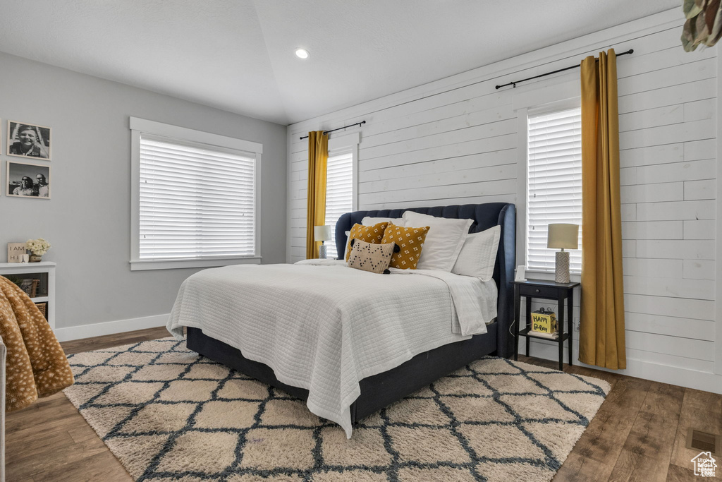 Bedroom with wood finished floors, multiple windows, wooden walls, and recessed lighting