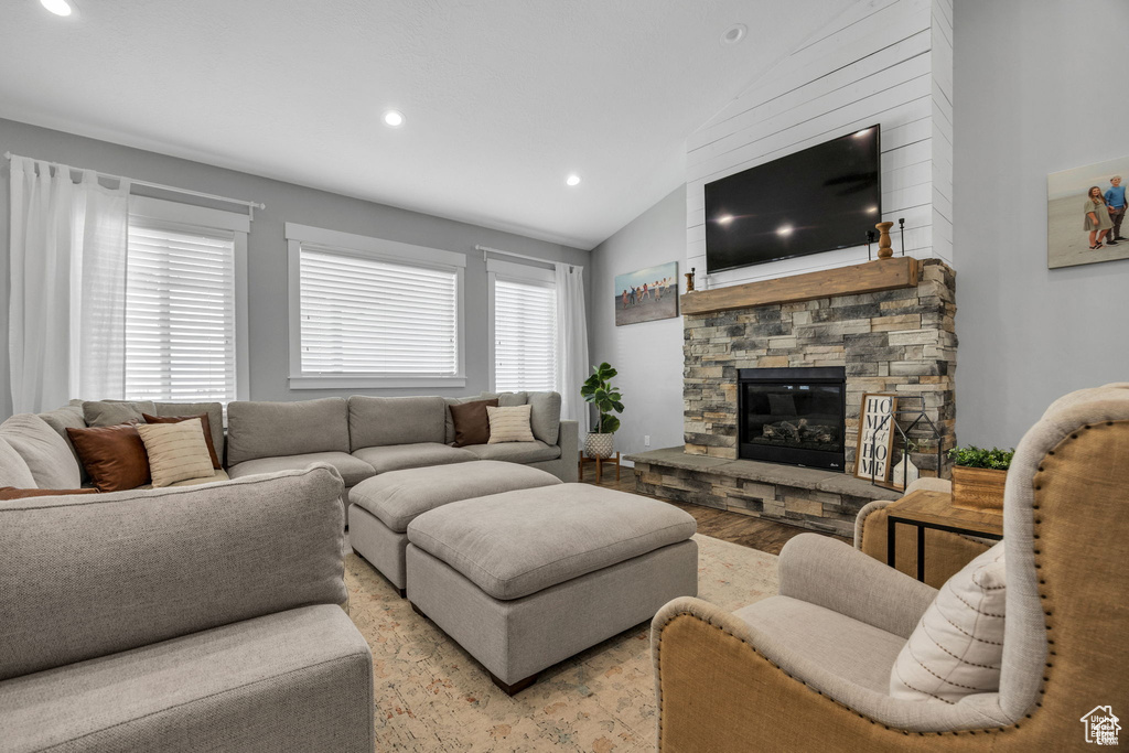 Living room featuring vaulted ceiling, a fireplace, recessed lighting, and light wood-style flooring