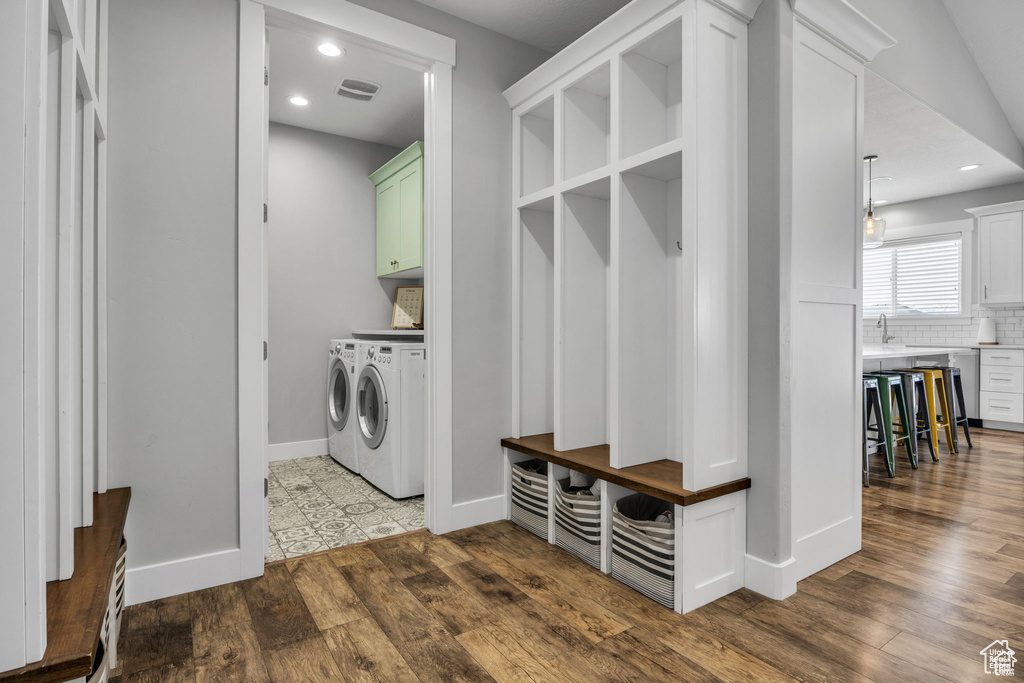 Washroom with independent washer and dryer, cabinet space, dark wood finished floors, and recessed lighting
