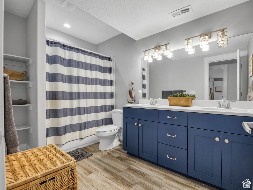 Full bath featuring double vanity, wood finished floors, curtained shower, and recessed lighting