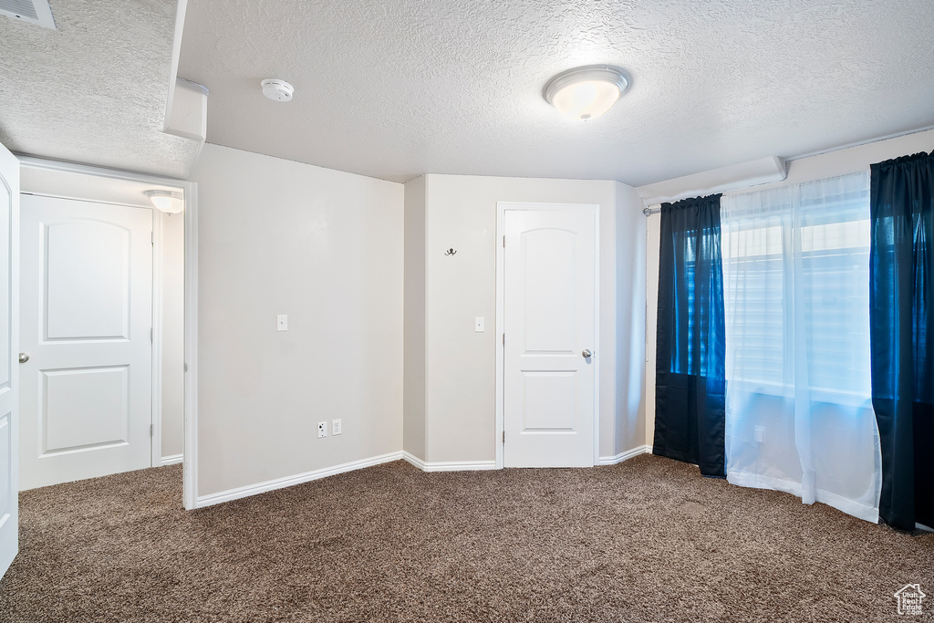 Unfurnished bedroom with a textured ceiling and carpet floors