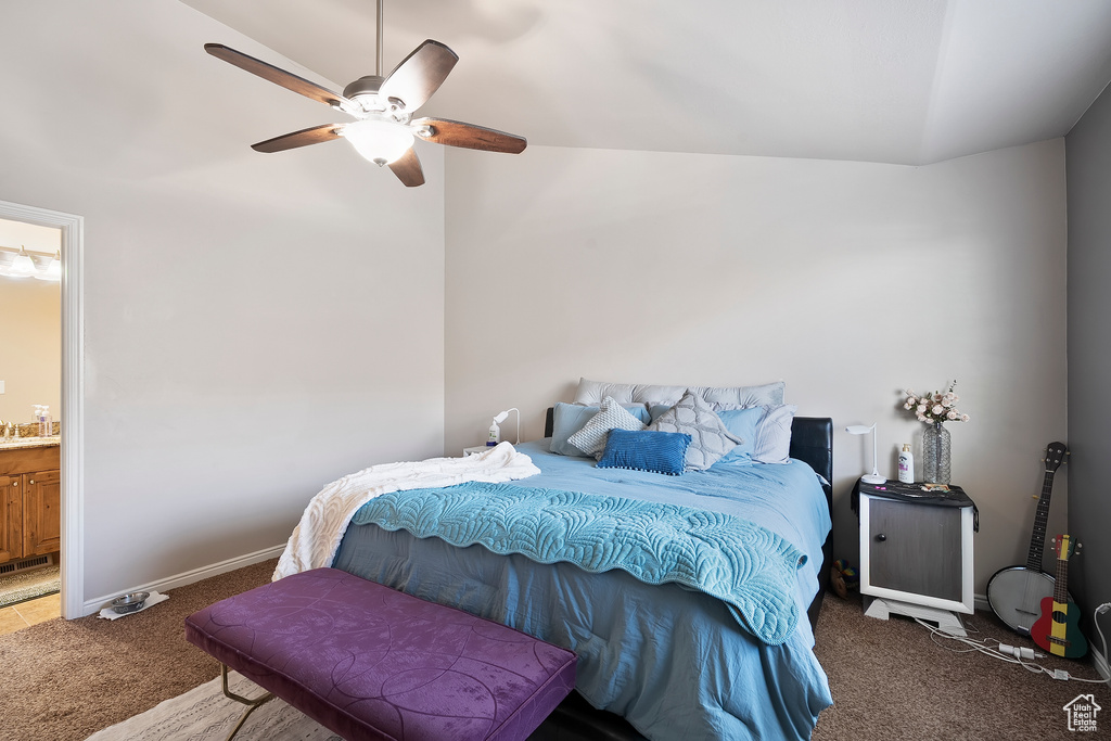 Carpeted bedroom with vaulted ceiling, connected bathroom, and ceiling fan