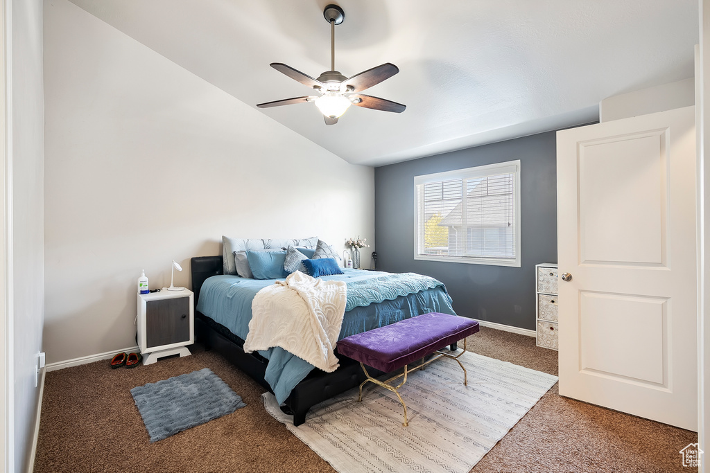 Carpeted bedroom featuring lofted ceiling and a ceiling fan