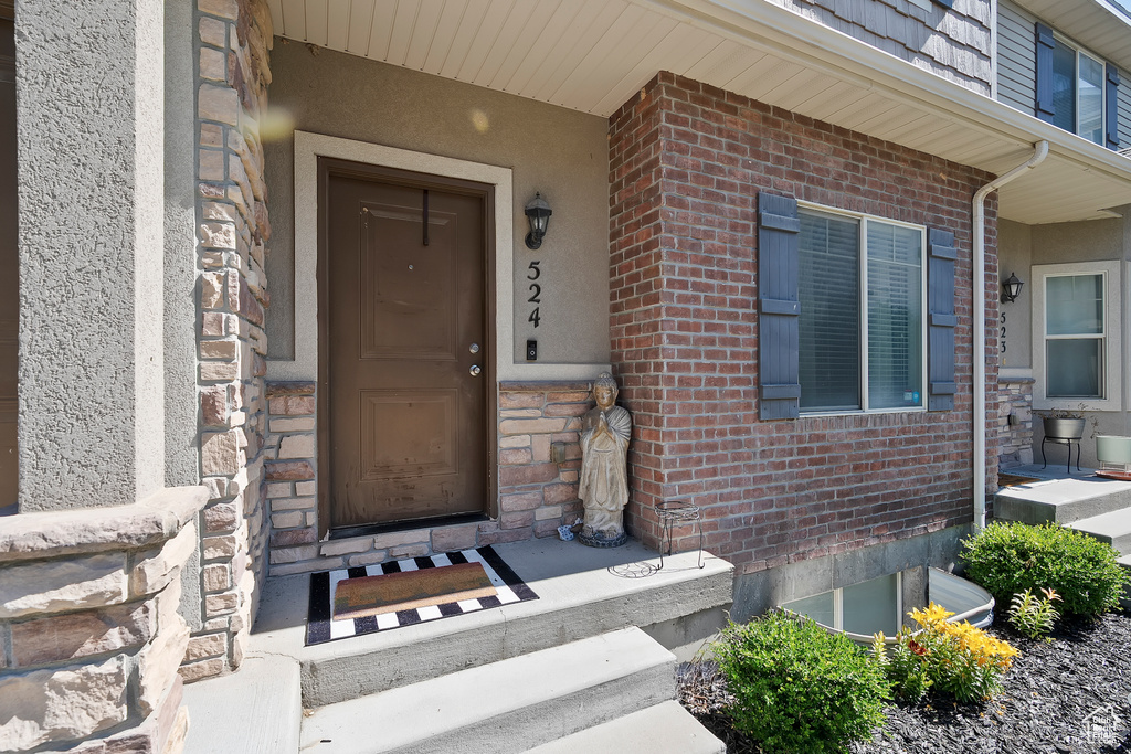 Doorway to property featuring brick siding and stucco siding