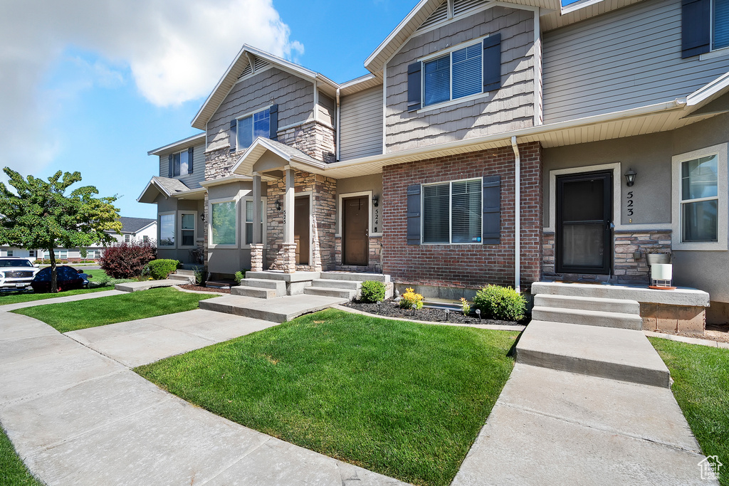 View of front of house with a front lawn, stone siding, and brick siding