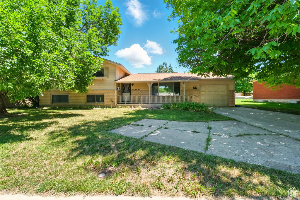 Split level home featuring brick siding, driveway, a garage, and a front lawn