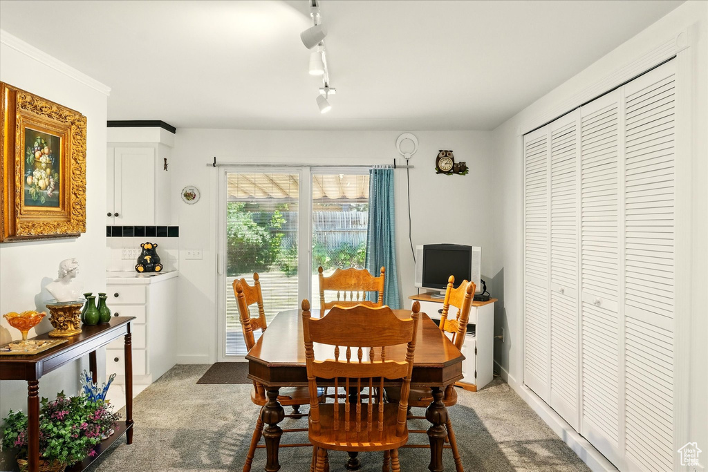 Dining space featuring light colored carpet, rail lighting, and baseboards
