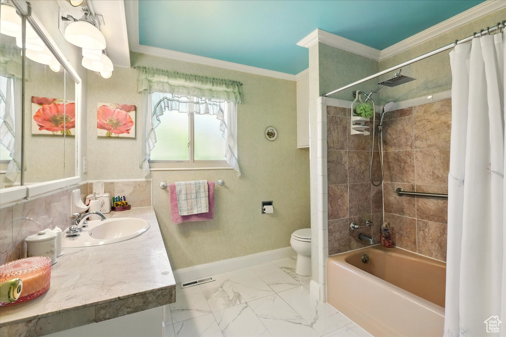 Bathroom with toilet, vanity, ornamental molding, shower / bath combo, and baseboards