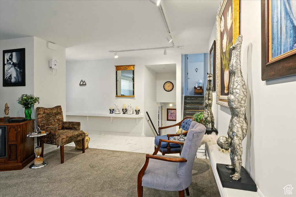 Sitting room featuring track lighting, stairway, and marble look tiles