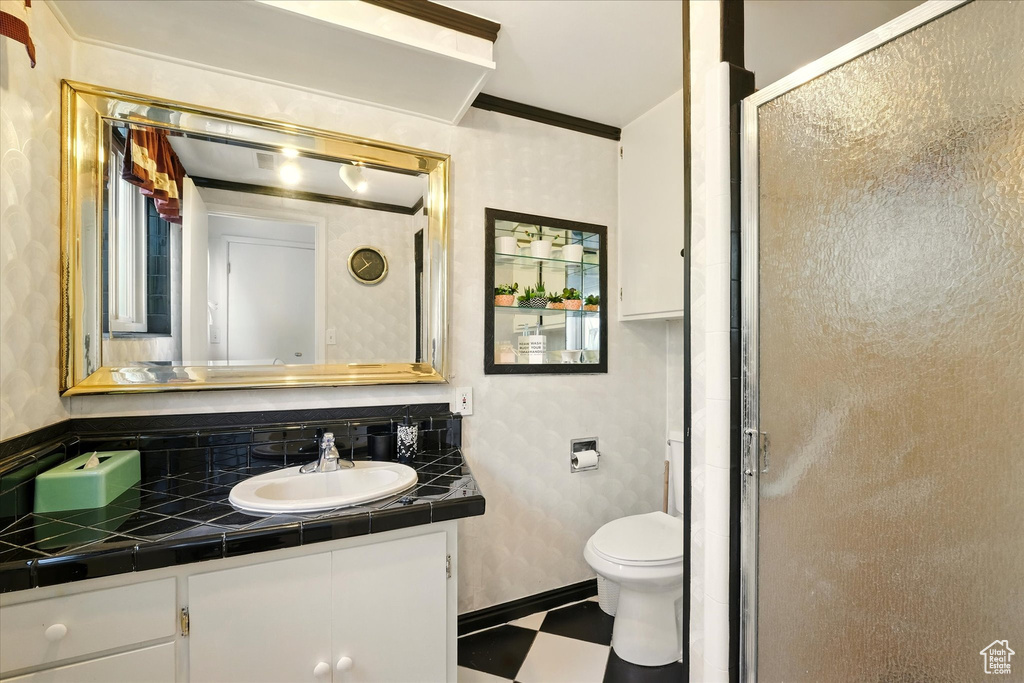 Bathroom featuring tile patterned floors, vanity, a stall shower, toilet, and crown molding