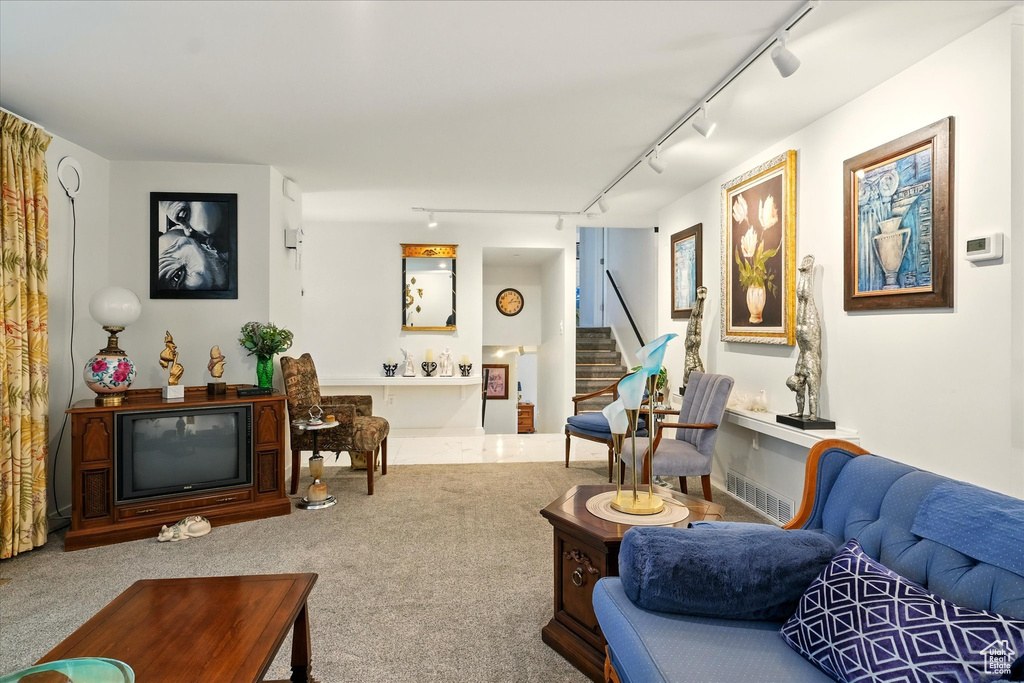 Living room with track lighting, stairs, and carpet flooring
