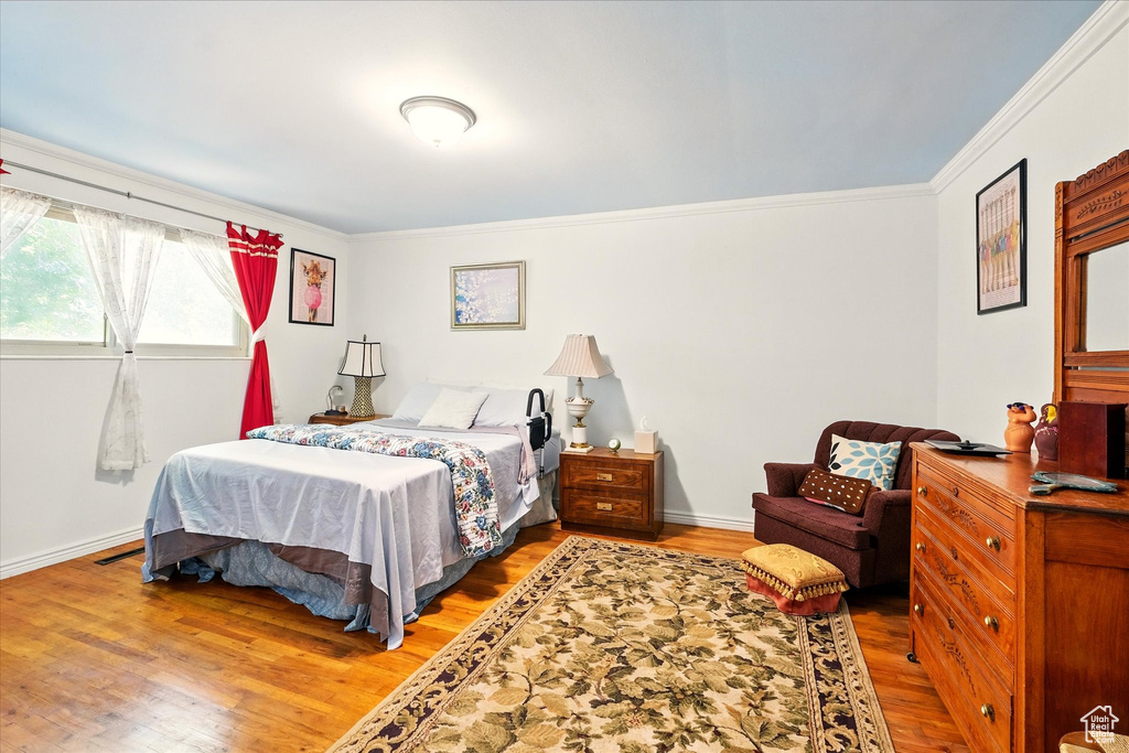 Bedroom featuring ornamental molding, wood finished floors, and baseboards