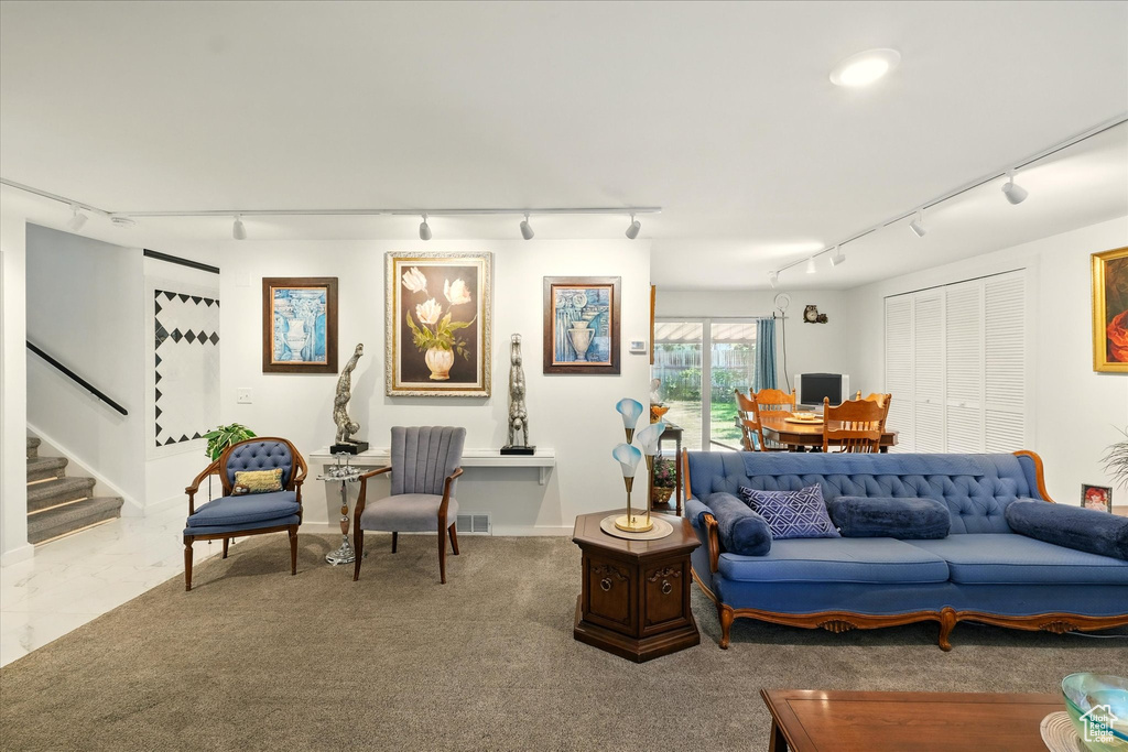 Living area featuring rail lighting, stairs, and baseboards