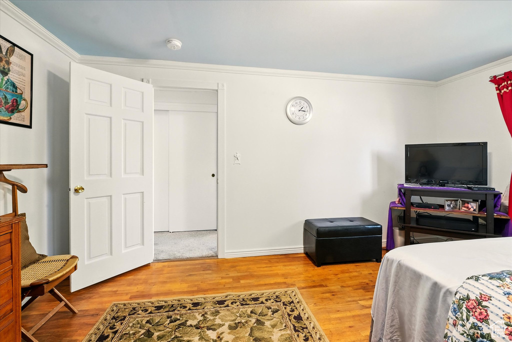 Bedroom featuring ornamental molding, wood finished floors, and baseboards