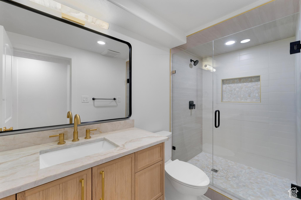 Bathroom featuring toilet, vanity, a shower stall, and recessed lighting