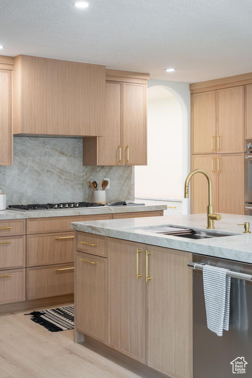 Kitchen with light brown cabinetry, appliances with stainless steel finishes, a sink, backsplash, and recessed lighting