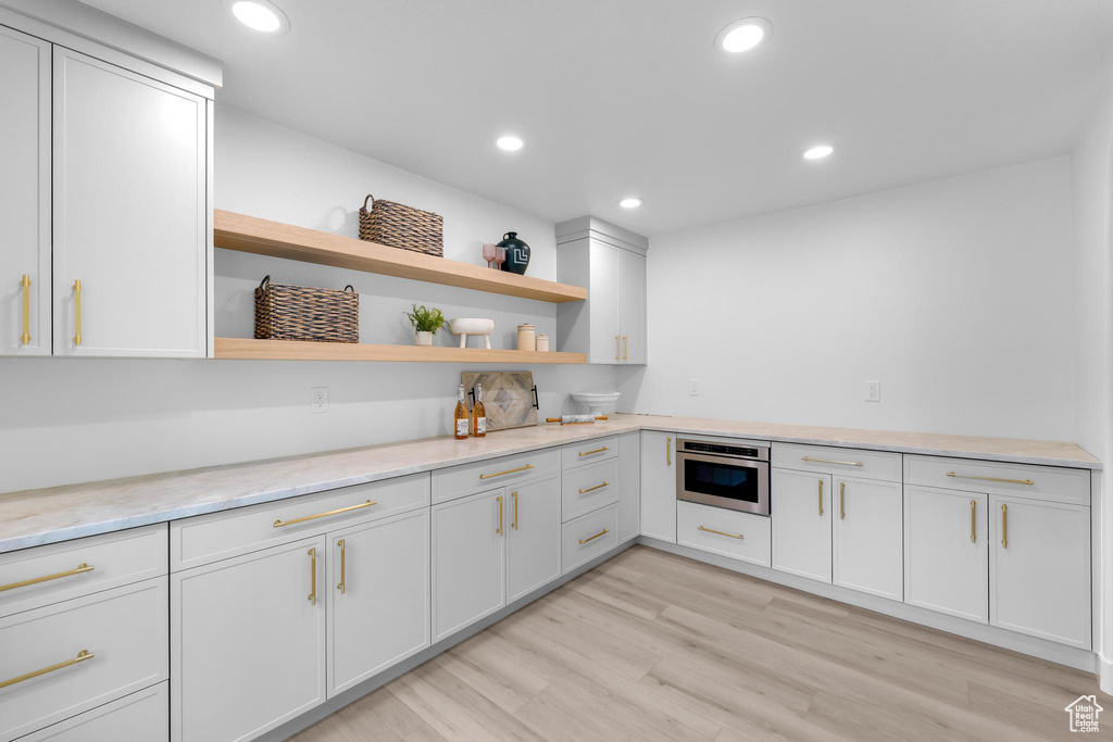Kitchen featuring oven, open shelves, recessed lighting, white cabinets, and light stone countertops