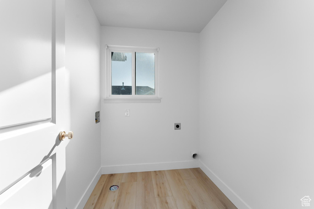 Laundry area featuring hookup for an electric dryer, light wood-style flooring, and baseboards