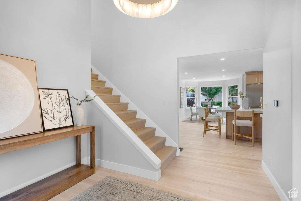Stairway featuring wood finished floors, a towering ceiling, baseboards, and recessed lighting