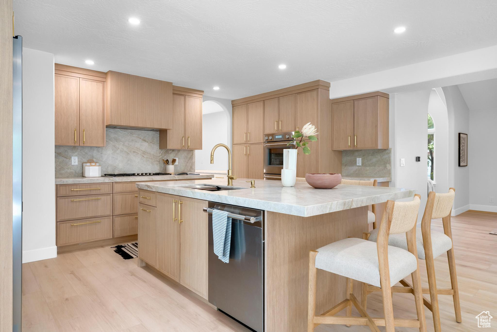 Kitchen with stainless steel appliances, a sink, light brown cabinets, light countertops, and recessed lighting