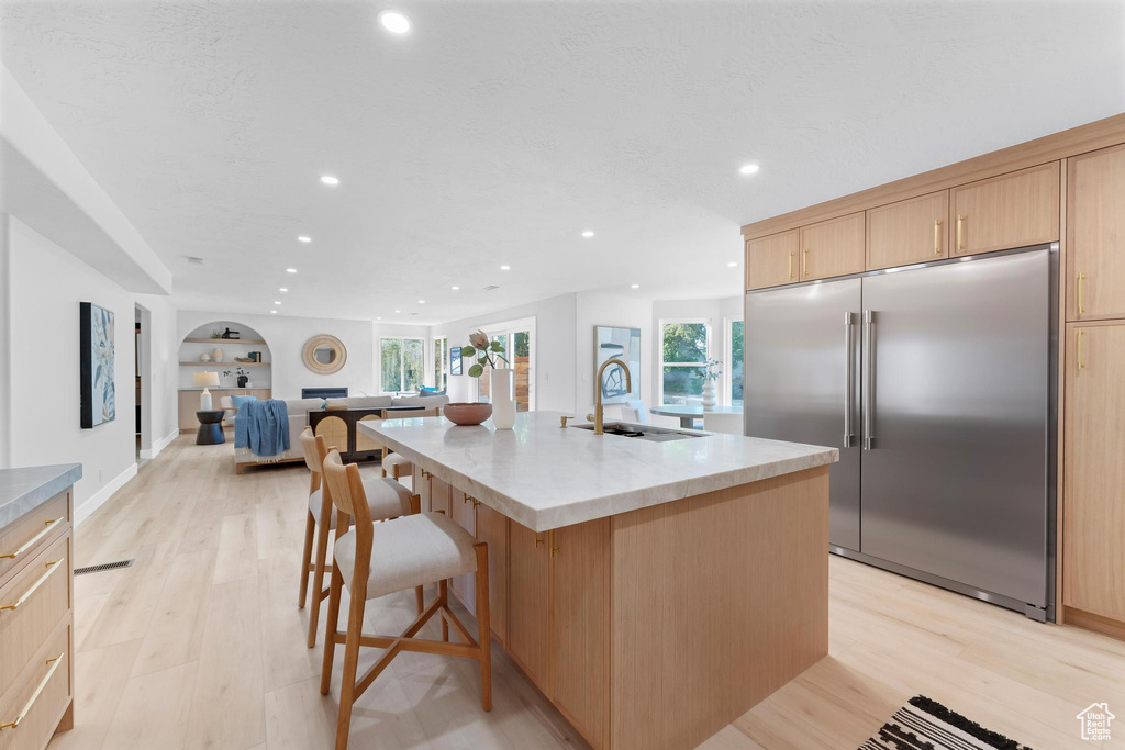 Kitchen featuring built in refrigerator, a sink, light brown cabinets, recessed lighting, and light wood-style flooring