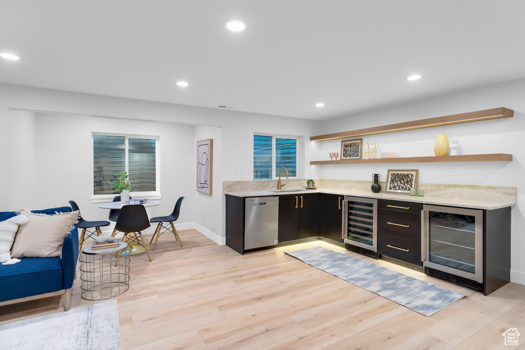 Indoor dry bar featuring beverage cooler, stainless steel dishwasher, light wood finished floors, baseboards, and recessed lighting